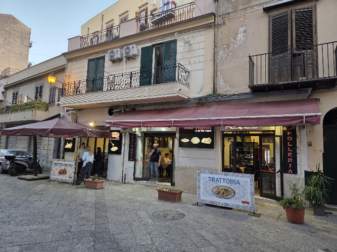 La facciata in via dei Candelai: tende bordeaux, insegna verticale della polleria e il pannello di maiolica sul cavalletto